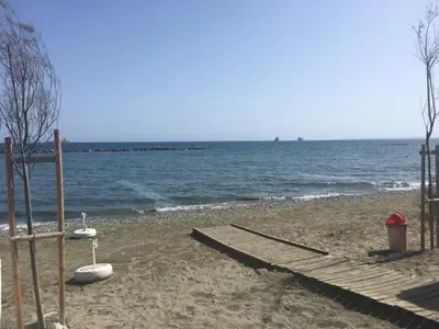 a sandy beach with a dock and the water at Despoina Town House in Limassol
