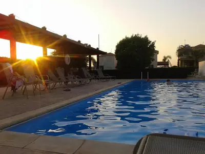 a swimming pool with the sun reflecting on the water at Sunset Garden Villa in Pervolia