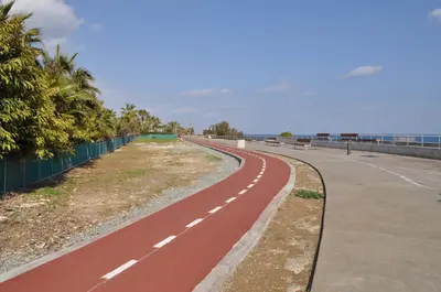 a red road next to the ocean with a fence at Sunset Garden Villa in Pervolia