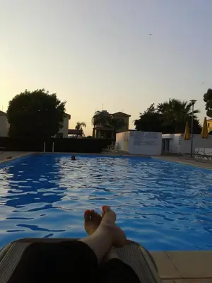 a person laying on the edge of a swimming pool at Sunset Garden Villa in Pervolia