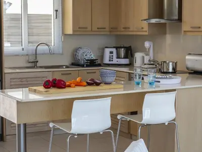 a kitchen with a counter with two white bar stools at Passion Villa in Protaras