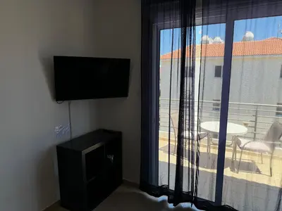 a room with a flat screen tv and a window at Apartment at luxurious Mythical Sands Resort in Paralimni