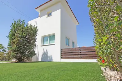 a white house with a wooden fence and a yard at Villa Anette in Protaras