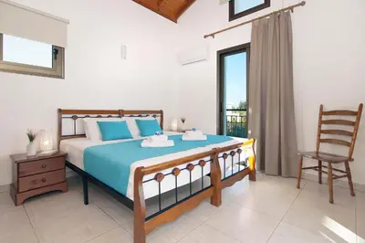 a bedroom with a bed with a chair and a window at Villa Ingrid in Ayia Napa
