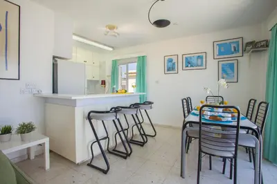 a kitchen and dining room with a table and stools at Protaras Holiday Suite Annie in Protaras