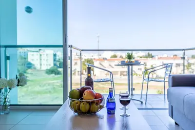 a bowl of fruit and two glasses of wine on a table at Coralli Spa By Fig tree Bay in Protaras