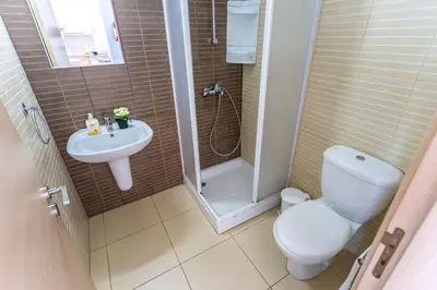 a bathroom with a shower and a toilet and a sink at Coralli Spa By Fig tree Bay in Protaras