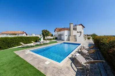 a swimming pool with chairs and a house at Kymma Villa #16 in Ayia Napa