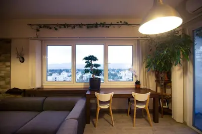 a living room with a couch and a table and two windows at Vas' Penthouse in Nicosia