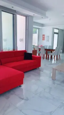 a red couch in a room with tables and chairs at Villa Spathele in Paralimni