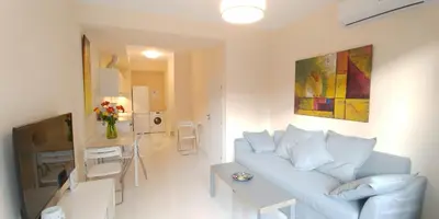 a white living room with a couch and a table at Galatex Beach Apartment in Limassol