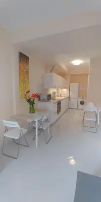 a white kitchen with a table and chairs at Galatex Beach Apartment in Limassol