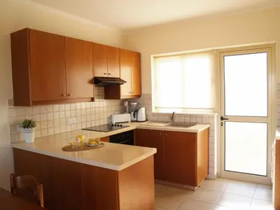 a kitchen with wooden cabinets and a counter top at Villas Ithaca Protaras in Protaras