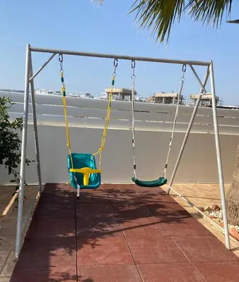 two swings on a porch with the ocean in the background at Villas Ithaca Protaras in Protaras