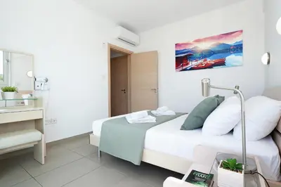 a white bedroom with a bed and a mirror at Apartment Victoria in Protaras