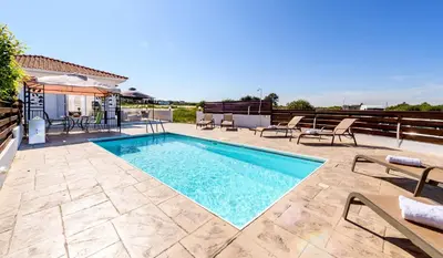 a swimming pool on a patio with chairs and a table at Sunset Villa Protaras in Protaras