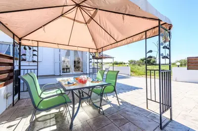 a patio with a table and chairs under a large umbrella at Sunset Villa Protaras in Protaras