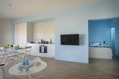 a living room with a table and a room with a bed at Azure Beachfront Suite in Protaras