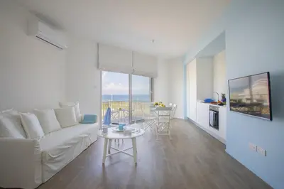 a living room with a white couch and a table at Azure Beachfront Suite in Protaras