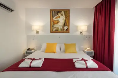 a bedroom with a bed with red curtains and a painting at Art & Wine Boutique Hotel in Larnaka