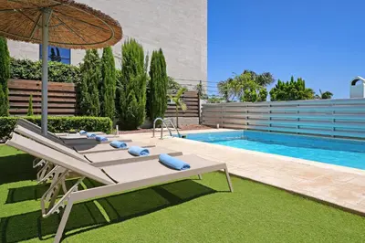 a pool with two lounge chairs and an umbrella at Villa Celine in Protaras