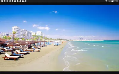 a beach with chairs and umbrellas and the ocean at Panikos Beach Apartment I in Larnaka