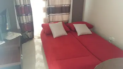 a red couch with two white pillows in a room at Panikos Beach Apartment I in Larnaka