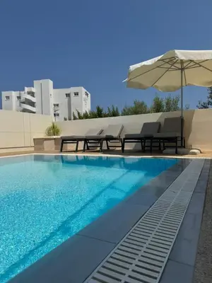 a swimming pool with two chairs and an umbrella at Villa Sotmarie in Protaras