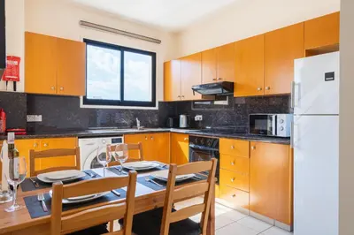a kitchen with a table and a white refrigerator at CityDen in Larnaka