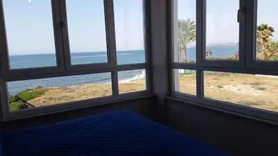 a bedroom with four windows looking out at the beach at Periyiali Beach Sunset Suite A7 in Pervolia