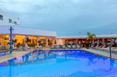 a large swimming pool with chairs and a hotel at Limanaki Beach Hotel & Suites in Ayia Napa