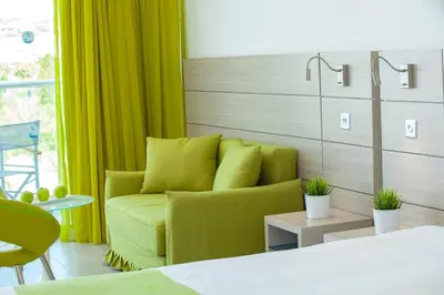 a living room with a green couch and a bed at Limanaki Beach Hotel & Suites in Ayia Napa