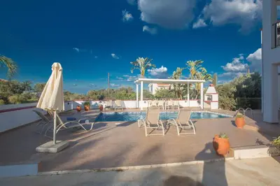 a pool with two chairs and an umbrella at Villa Orka in Protaras