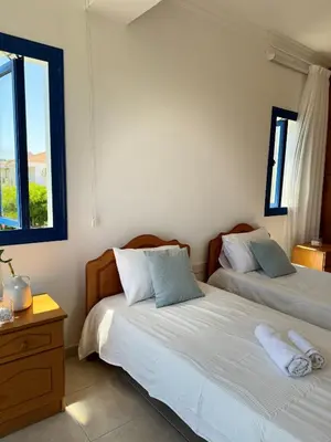 two beds in a room with two windows at Villa Jenny in Protaras