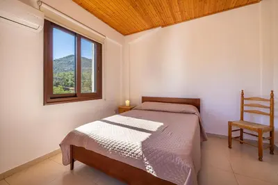 a bedroom with a bed and a window and a chair at The River House in Trimiklini