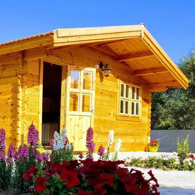 a small wooden cabin with flowers in front of it at Cyprus Glamping Park in Ayios Theodhoros
