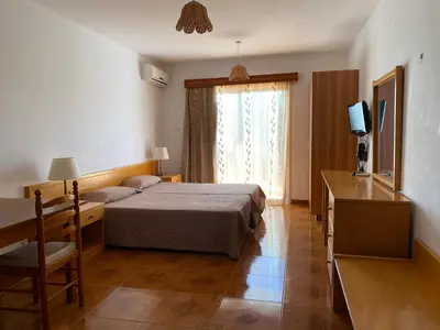 a bedroom with a bed and a tv and a window at Alexia Hotel Apartments in Ayia Napa