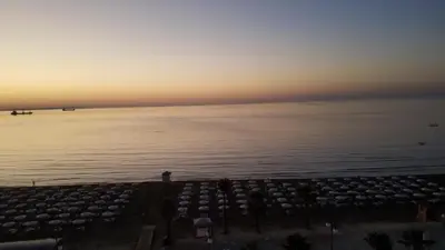 a sunset over the water with a lot of umbrellas at Alex Beach Apartment 33 in Larnaka