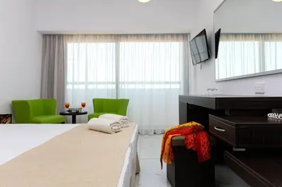 a hotel room with a bed and two green chairs at Christofinia Hotel in Ayia Napa