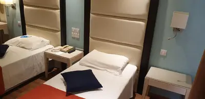 a small room with two beds and a mirror at Castelli Hotel Nicosia in Nicosia