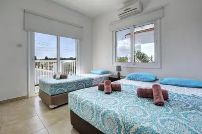 a bedroom with two beds and a balcony at Nissi Villa Gintare in Ayia Napa