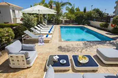 a swimming pool with lounge chairs and an umbrella at Villa Mylos 7 in Protaras