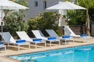 a row of white lounge chairs next to a swimming pool at Villa Mylos 7 in Protaras