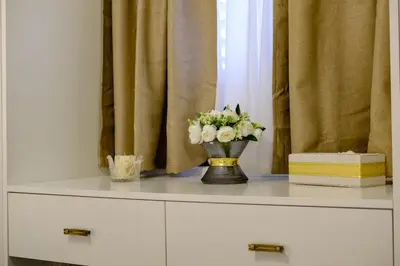 a vase of flowers on a dresser in front of a window at Lazuli Sea View Beachfront Ap 254 in Larnaka