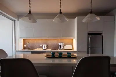 a kitchen with white cabinets and a table with chairs at Poseidon Apartment by Michalis in Ayia Napa