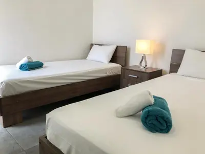 a bedroom with two beds and a blue towel on the bed at Poseidon Apartment by Michalis in Ayia Napa