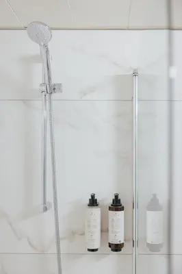 a shower in a bathroom with three bottles on a shelf at Odysseia Hotel Kapetanios in Limassol