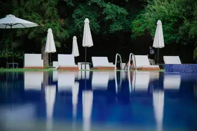 a swimming pool with white chairs and umbrellas at Odysseia Hotel Kapetanios in Limassol