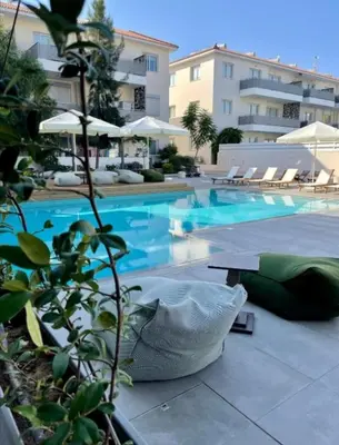 a swimming pool with a table next to a building at Mythical Sands Resort - Antonios in Paralimni
