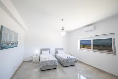 a white room with two beds and a window at Villa Marylou in Protaras